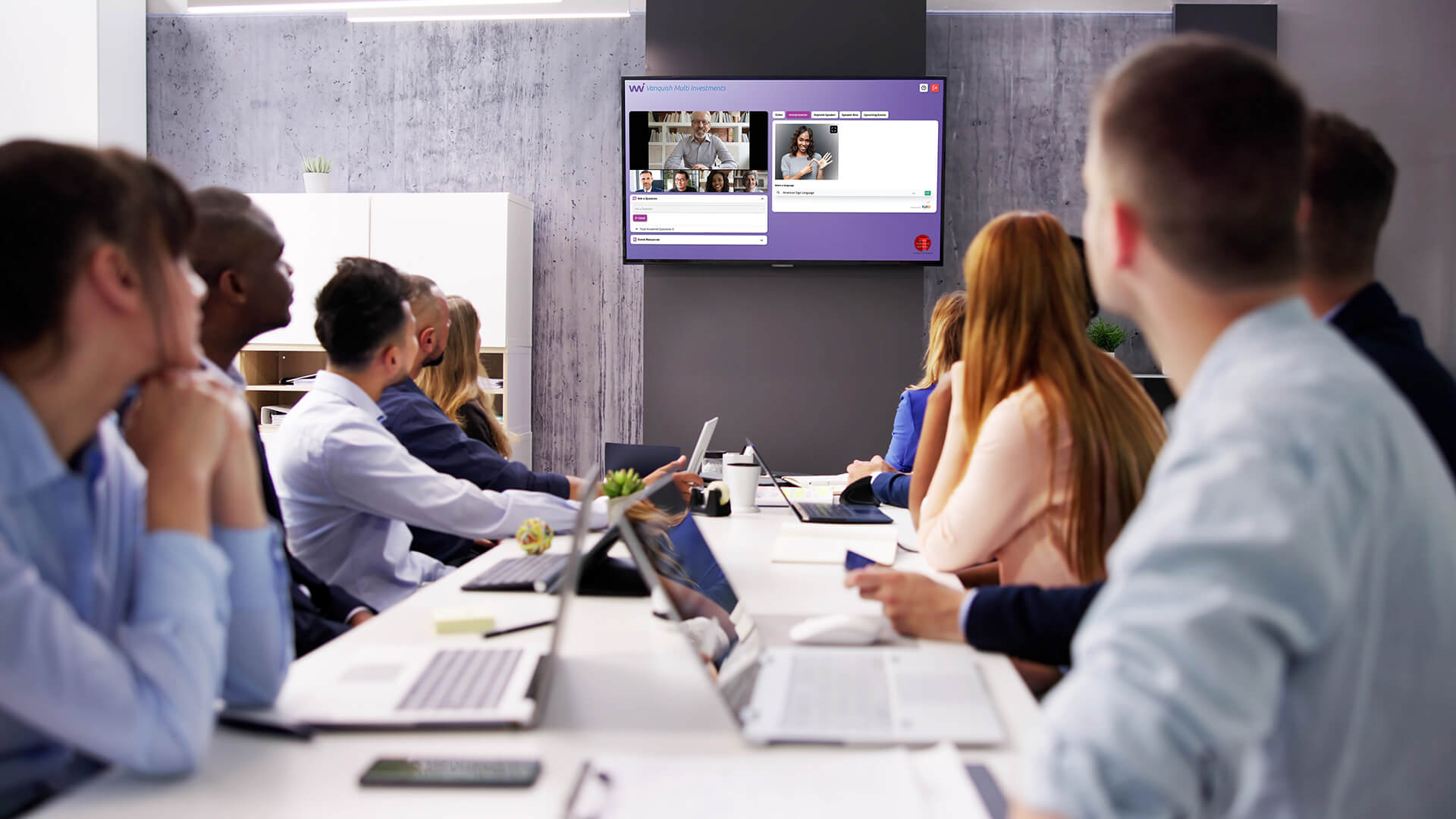 Group of people in an office watching an event with a sign language interpreter