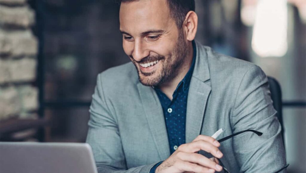 Man smiling while working on his laptop