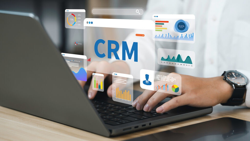 Graphic of a person working on a laptop with Marketing and CRM icons hovering over the keyboard