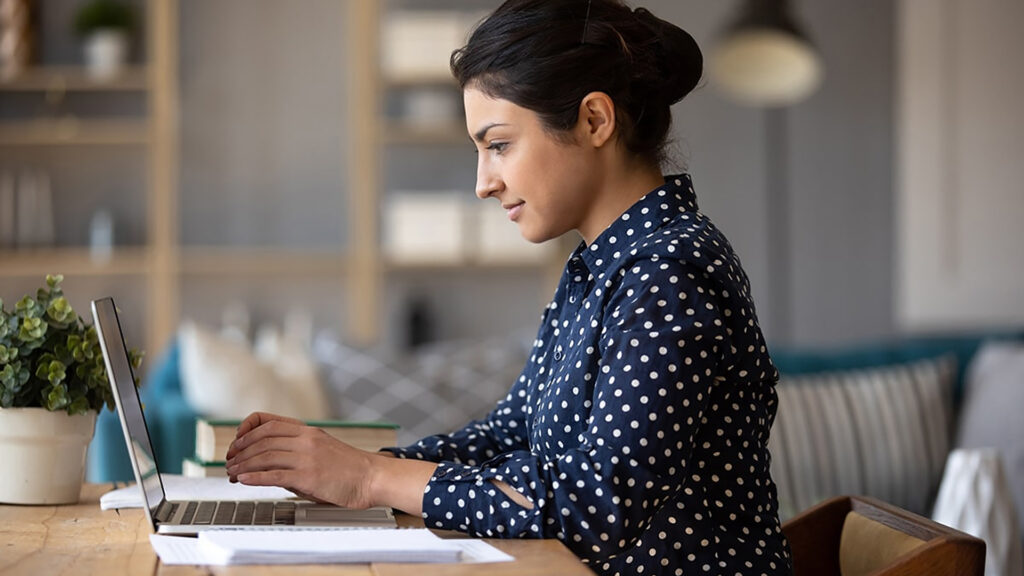 Business woman smiling and typing on her laptop