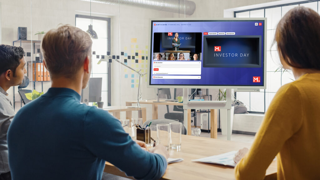 Group of people sitting at a table watching an event on a television