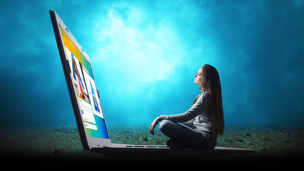 Women sitting on laptop keyboard outdoors looking at screen