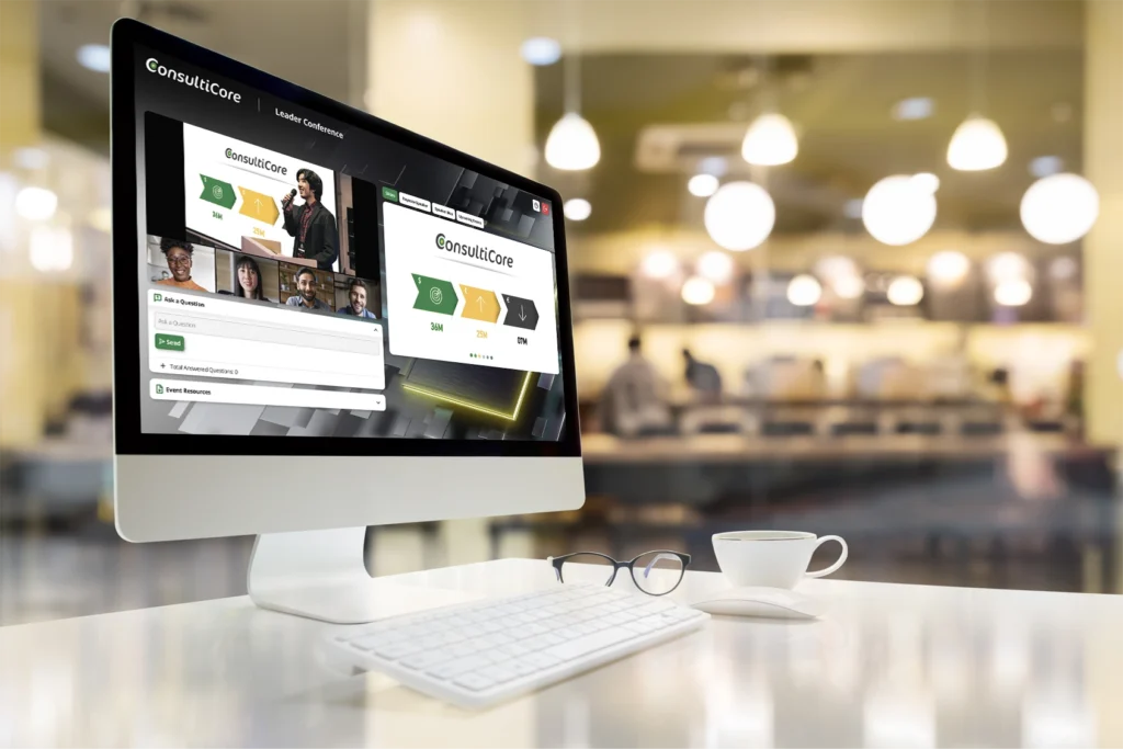 an image of a white computer in a coffee shop environment. A virtual townhall webcast using virtual event engagement tools is on the screen