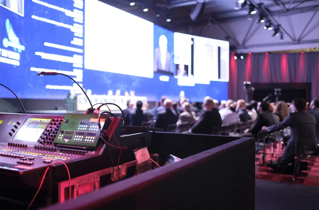 A wide shot of a conference in progress with recording equipment in the foreground
