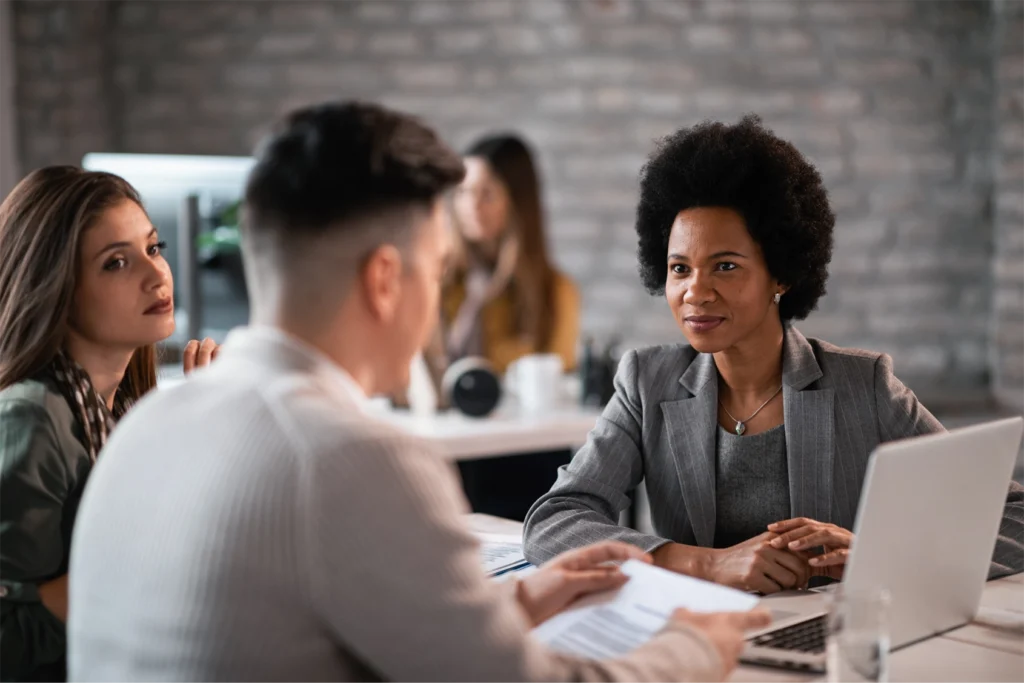 Three professionals sit in a group in an office as part of a HR onboarding event