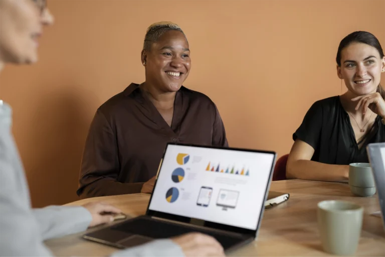 Three members of a marketing team sit at a table looking over inboud lead statistics